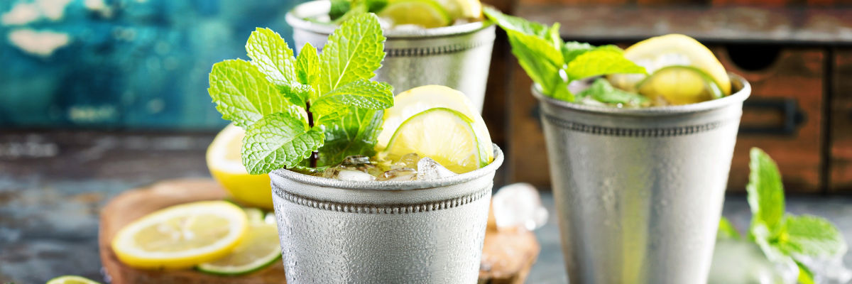 Mint Julep cocktails in silver cups with mint and lemon garnish.