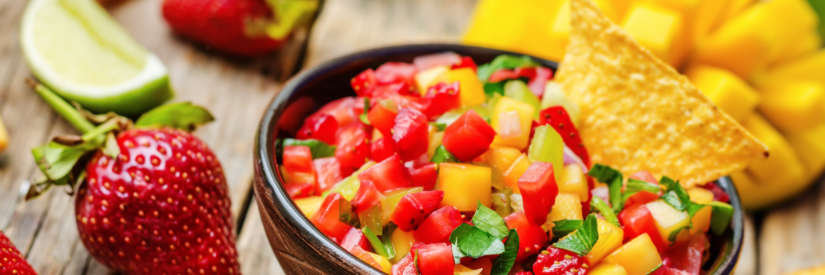A wooden background with strawberry mango salsa. 