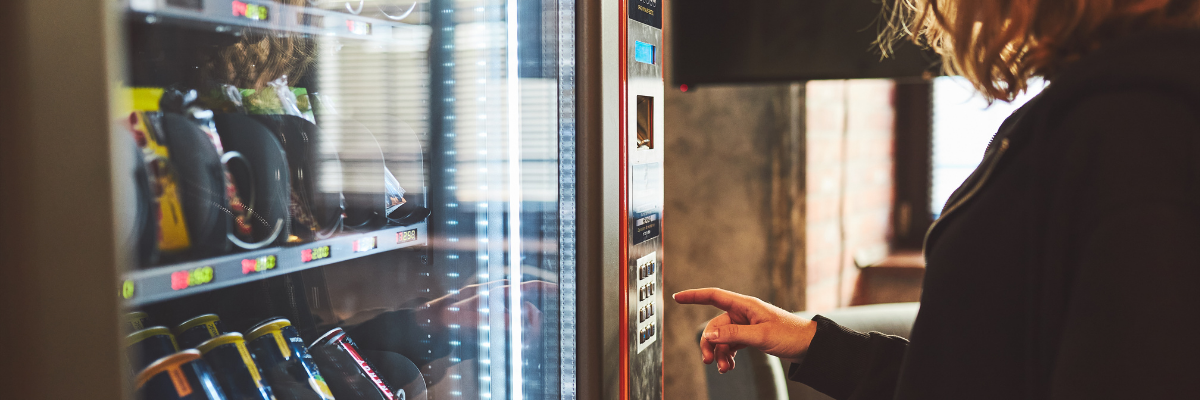 A woman stands in front of a snack vending machine.