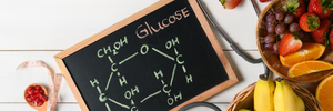 A chalkboard depicting the formula for glucose on a wooden surface with various produce items nearby.