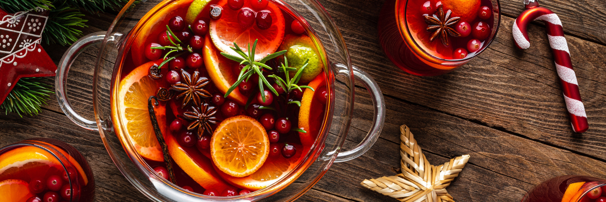 A punch bowl filled with Winter Spice Sangria garnished with cinnamon sticks on top of a winter holiday festive table.