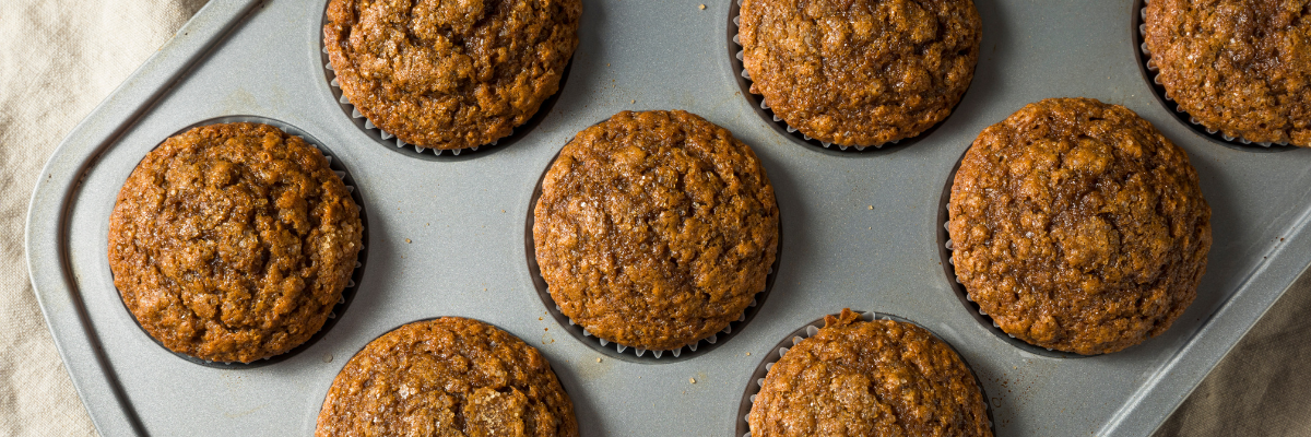 Gingerbread muffins in a muffin tin on a white cloth.