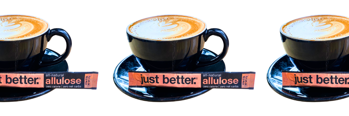 Three cups of cappuccino in a line with a stick pack of just better allulose.