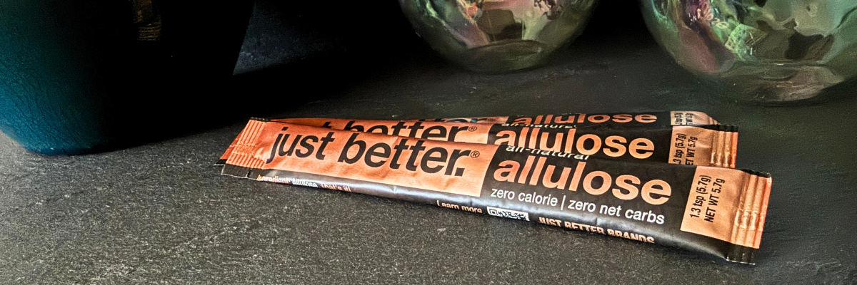 Several stick packs of just better allulose on a dark surface.