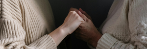 A woman holds hands with an elderly woman. 