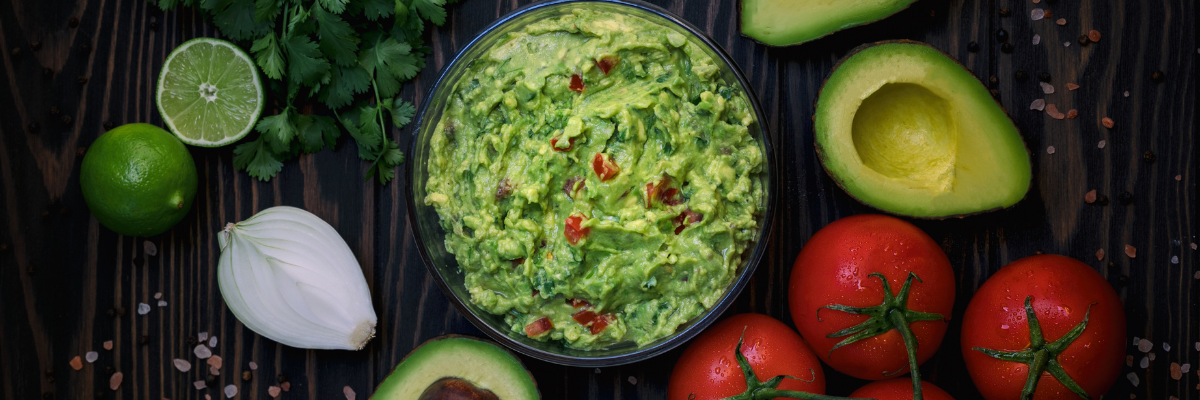 Spicy guacamole surrounded by ingredients for the dip.
