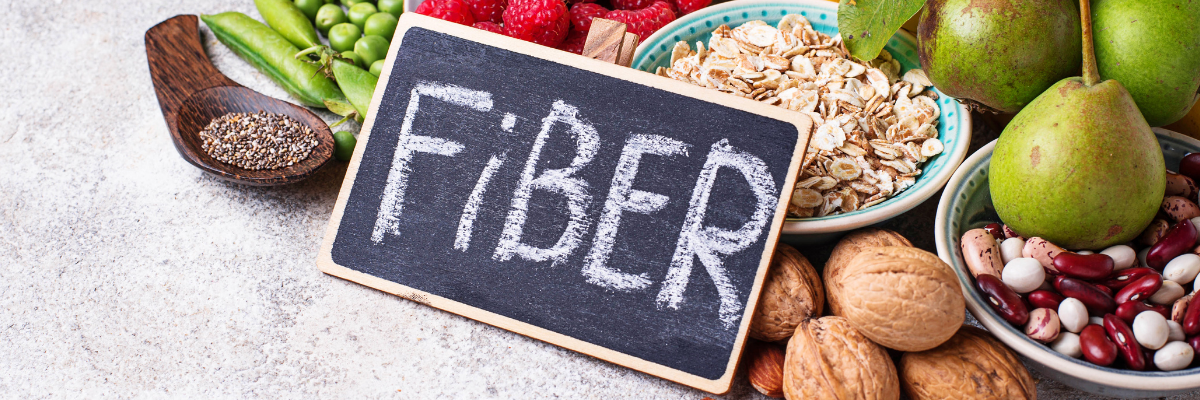 A stone countertop with various fiber-rich foods and a small chalkboard with the word FIBER written in chalk.