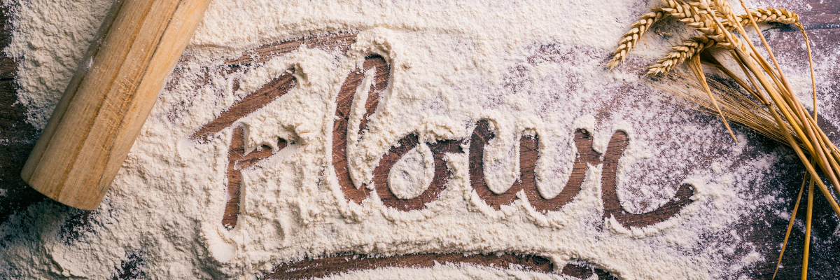 Whole wheat flour on a countertop with the word flour spelled out in flour.