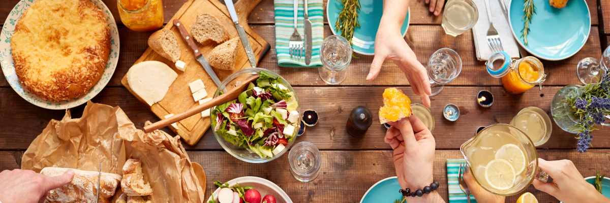 People at a table with various foods like bread and fruit.