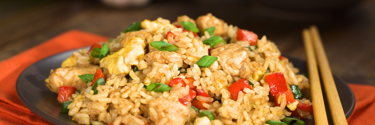 Veggie fried rice on a plate with chopsticks resting on the side of the plate.