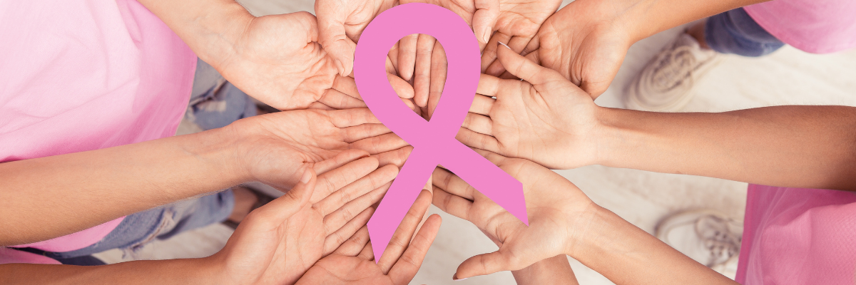A circle of women's hands holding a pink breast cancer awareness ribbon.