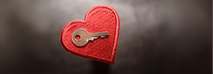 A cloth heart with a small key laying on top of it. 