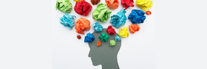 A gray silhouette on a white background with colorful balls of crumpled paper scattered above the head. 