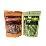 Two packages of 'just better' stick packs, one orange and one green, on a white background.